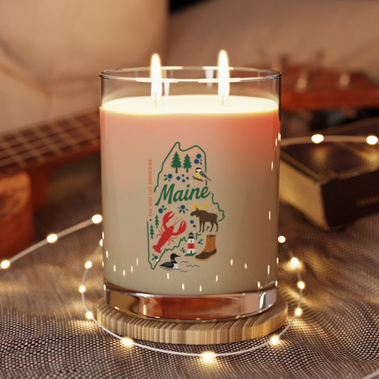 Candle with 'Maine' design on a wooden coaster with string lights in the background